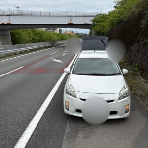 早朝の西富士道路にて、タイヤバーストのため高架下の路肩に安全に退避している白い乗用車